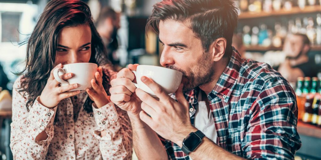 Schönes junges Paar, das Kaffee trinkt und einander ansieht