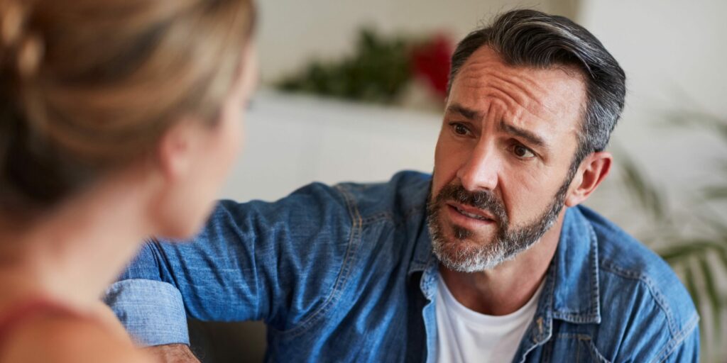 Schnappschuss eines reifen Mannes, der besorgt aussieht, während er zu Hause ein Gespräch mit seiner Frau führt