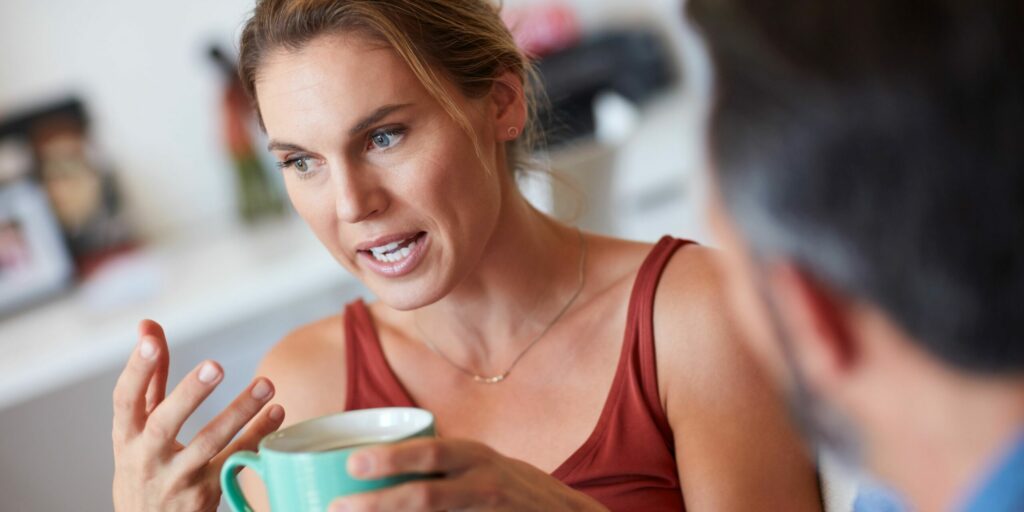 Schnappschuss einer attraktiven jungen Frau, die ein ernstes Gespräch mit ihrem Mann führt, während sie eine Tasse Kaffee in der Hand hält