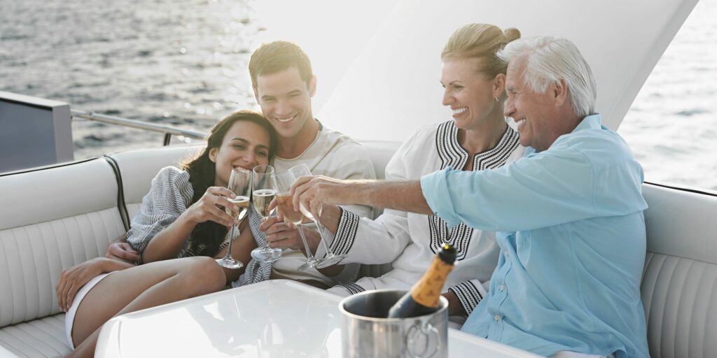 Junges und älteres Paar stoßen auf dem Boot mit Sekt an.