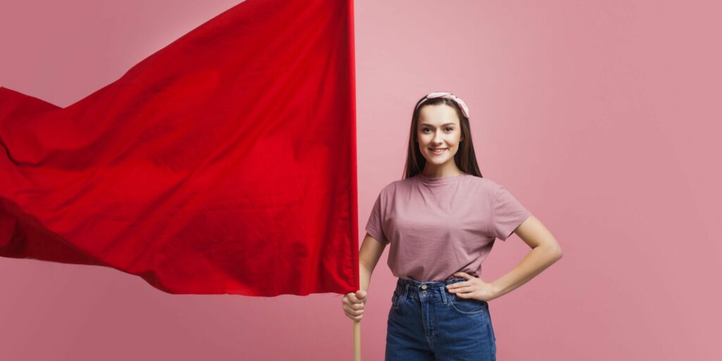 Aktivistin und Revolutionärin, junge Frau mit roter Fahne auf rosa Hintergrund. Feminismus und der Kampf um Rechte, Konzept