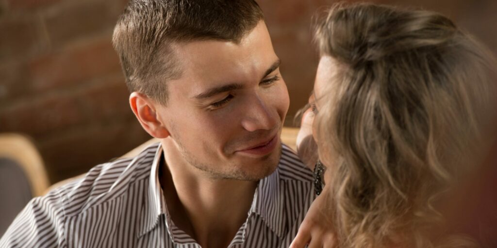 Paar prostet Weingläser an, während es im Restaurant sitzt und ein romantisches Date hat